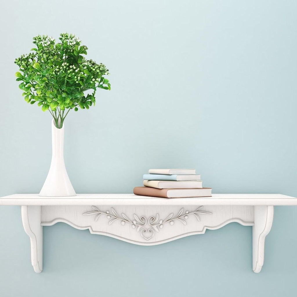 White table with a vase of greenery and books against a light blue wall