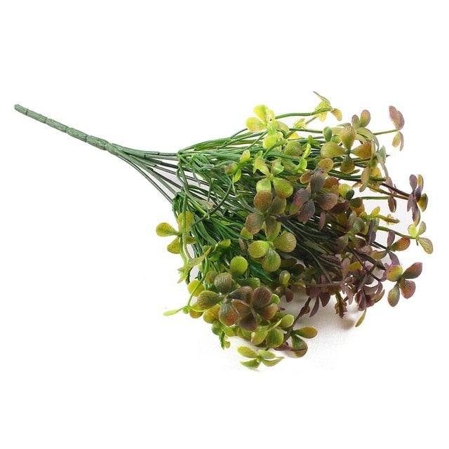 Bouquet of artificial green and purple flowers on a white background