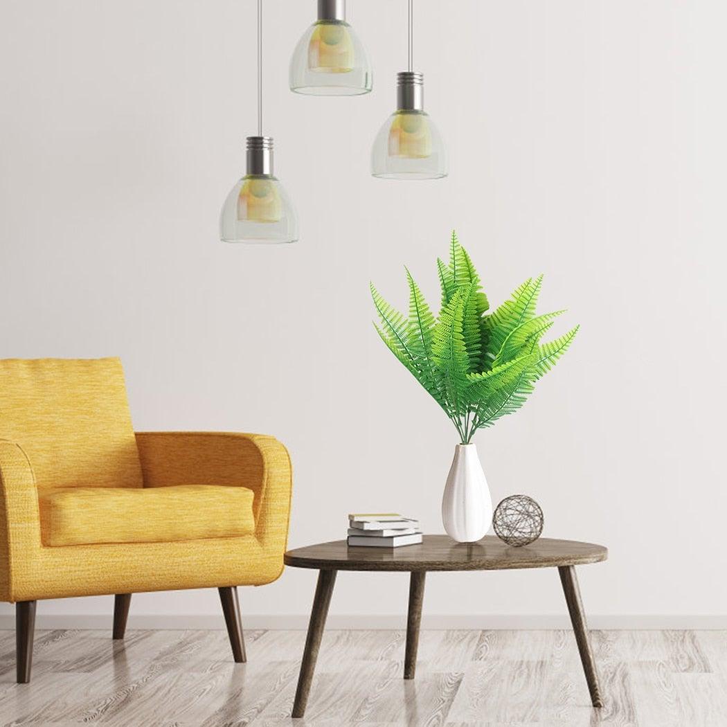 Yellow armchair and wooden side table with a plant in a white vase against a light gray wall.
