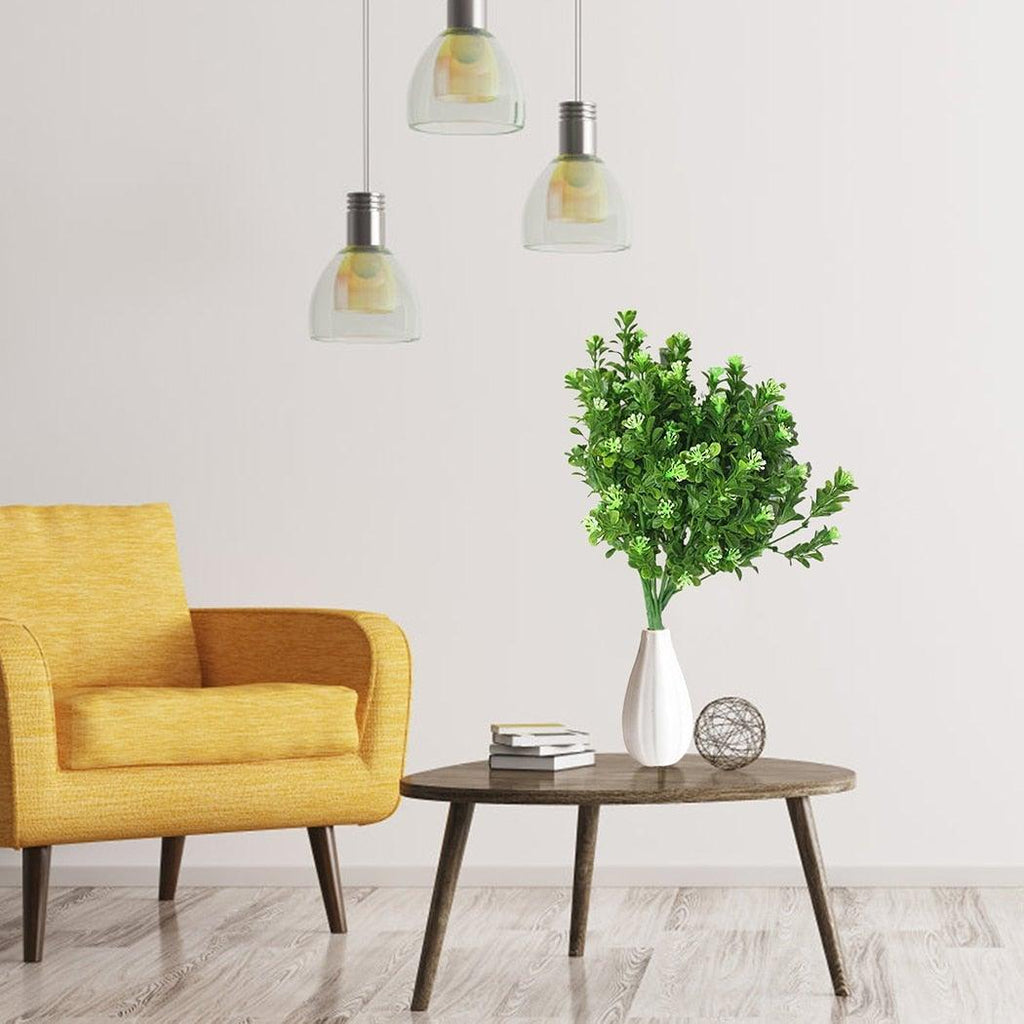 Yellow armchair next to a wooden side table with a vase of greenery in a minimalistic room.