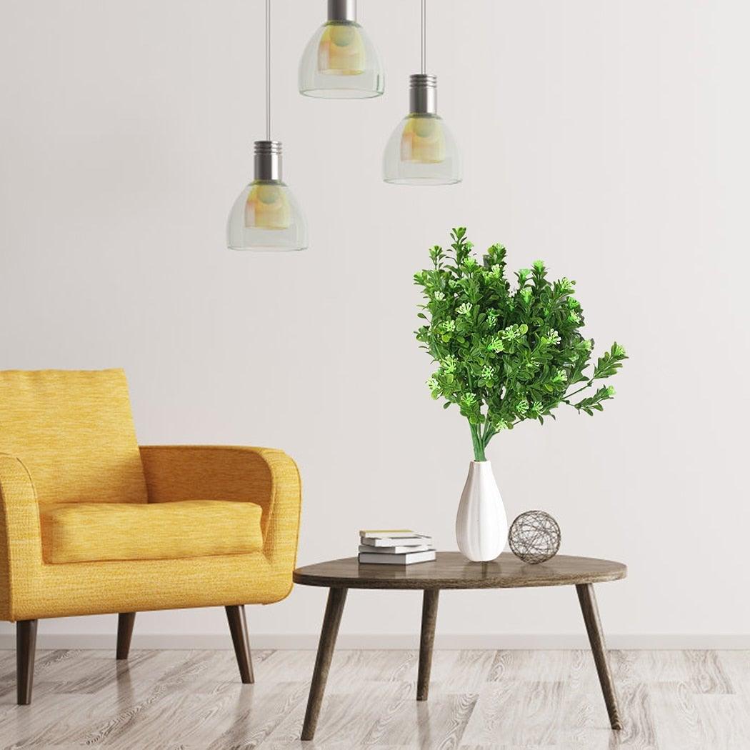 Yellow armchair next to a wooden side table with a vase of greenery in a minimalistic room.