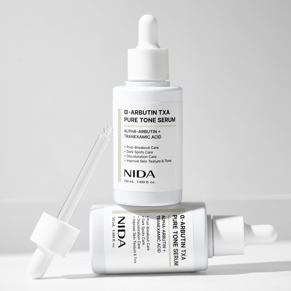 NIDA Q-Arbutin TXA Pure Tone Serum bottle with dropper on a light gray background