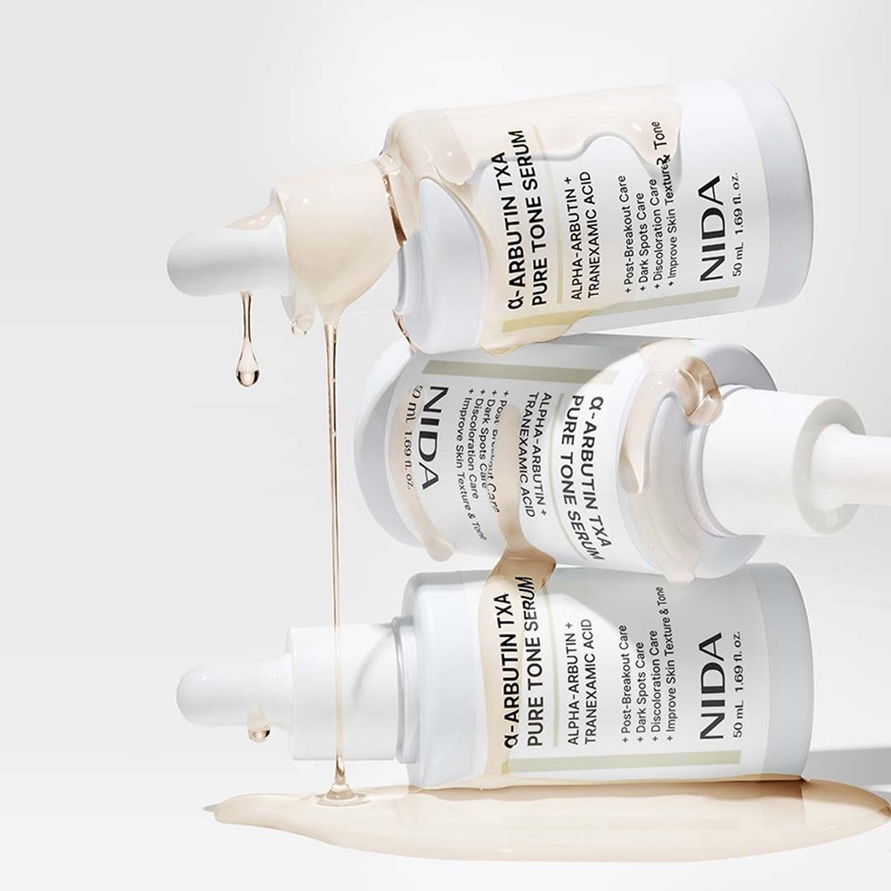NIDA skincare serum bottles with dropper on a light gray background