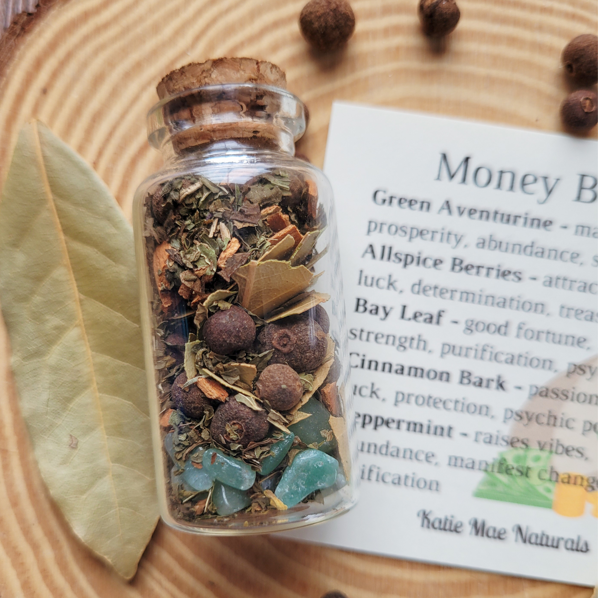 Money Bowl spell jar with green aventurine, bay leaf, allspice berries, cinnamon bark, peppermint and dried herbs for prosperity and abundance.