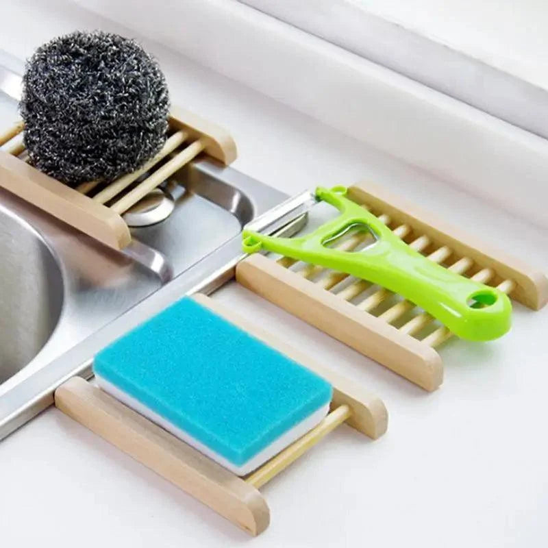 Kitchen sink caddy with sponge, scrubber, and other utensils on a white countertop.