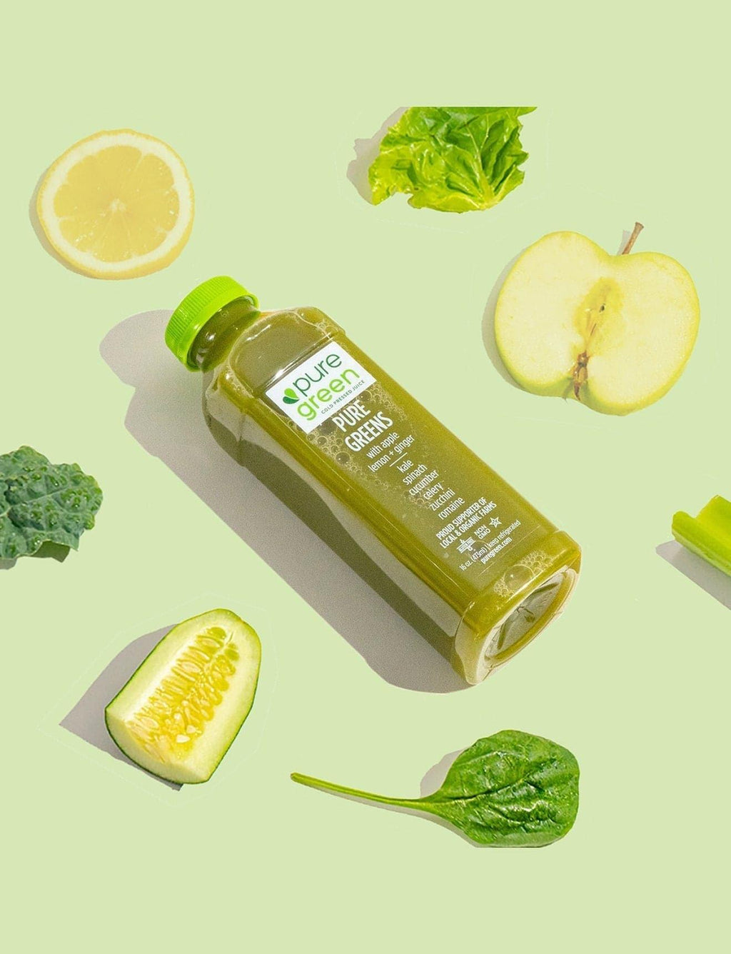 Bottle of green juice with fresh vegetables on a light green background. PURE GREENS ALG: Cold-Pressed NON-GMO Juice Drink with with Apple, Lemon, Ginger, Kale, Spinach, Cucumber, Celery, Zucchini and Romaine, No Added Sugar, Gluten-Free