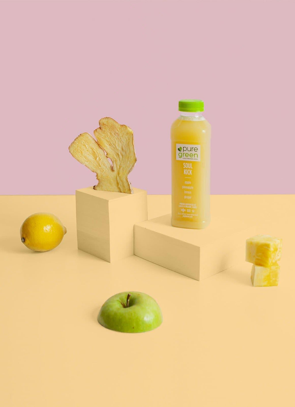 Juice bottle with a green lid on a yellow platform with fruits and a pink background. PURE GREEN SOUL KICK: Cold-Pressed NON-GMO Juice Drink with Apple, Pineapple, Lemon and Ginger, No Added Sugar, Gluten-Free