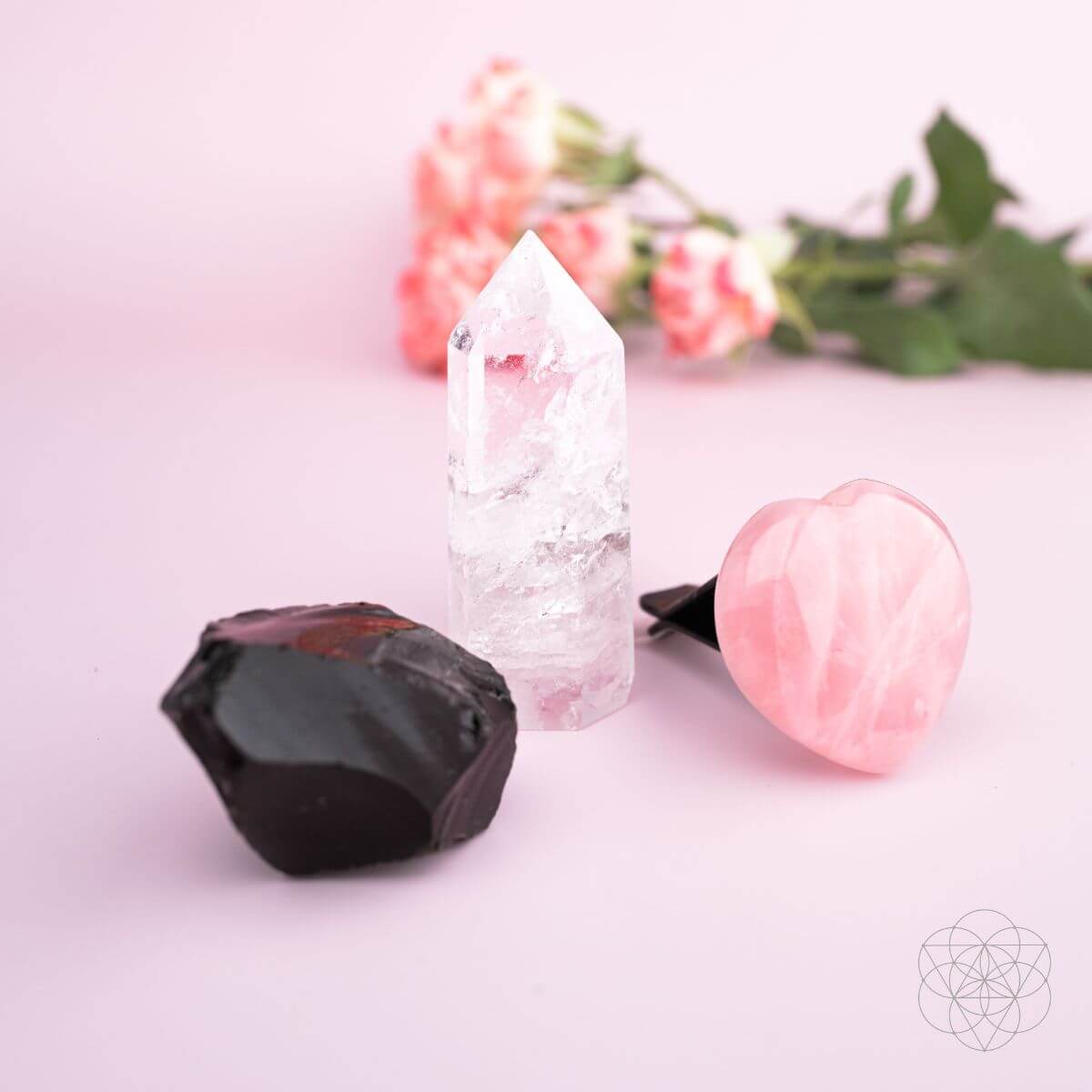 Three crystals on a light pink surface with blurred flowers in the background Spiritual GPS Guardian Car Vent Crystal Clip Kit | Protection Crystals for Safe Travel & Positive Energy