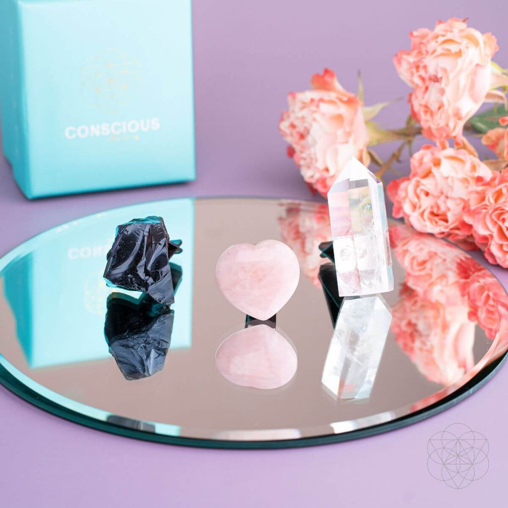 Mirror with crystals on a purple surface, next to a turquoise box and pink flowers. Spiritual GPS Guardian Car Vent Crystal Clip Kit | Protection Crystals for Safe Travel & Positive Energy