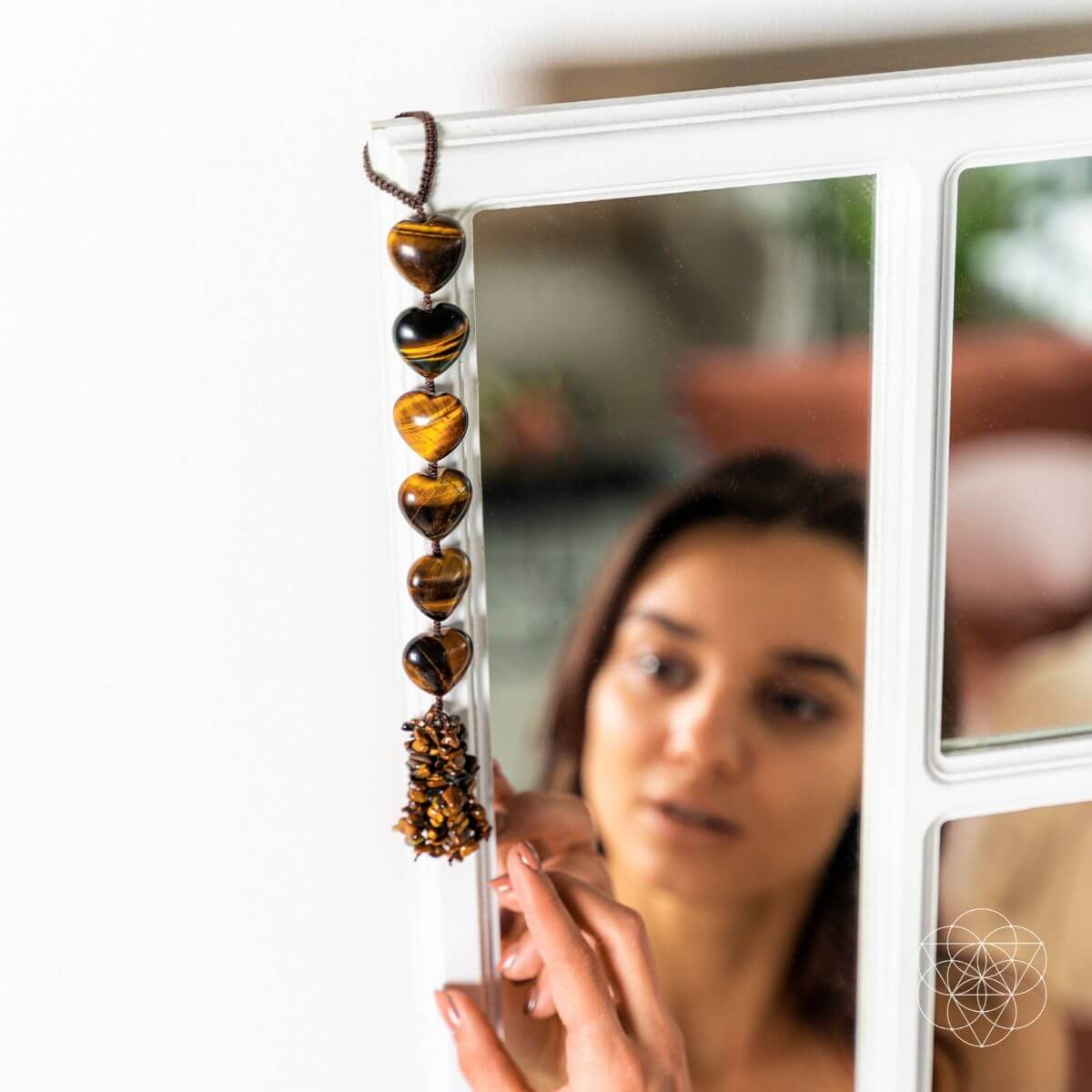 Woman holding a string of heart-shaped beads in front of a mirror Protection Tassel with Tiger's Eye Crystal for Protection, Positive Energy & Car Charm