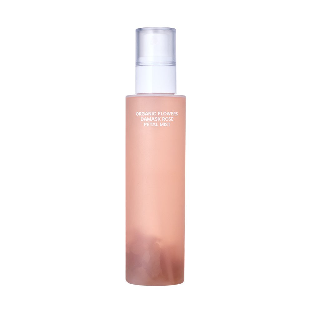 A tall, cylindrical bottle of Organic Flowers Damask Rose Petal Mist, featuring a translucent peach-pink body and a clear cap, set against a solid white background.