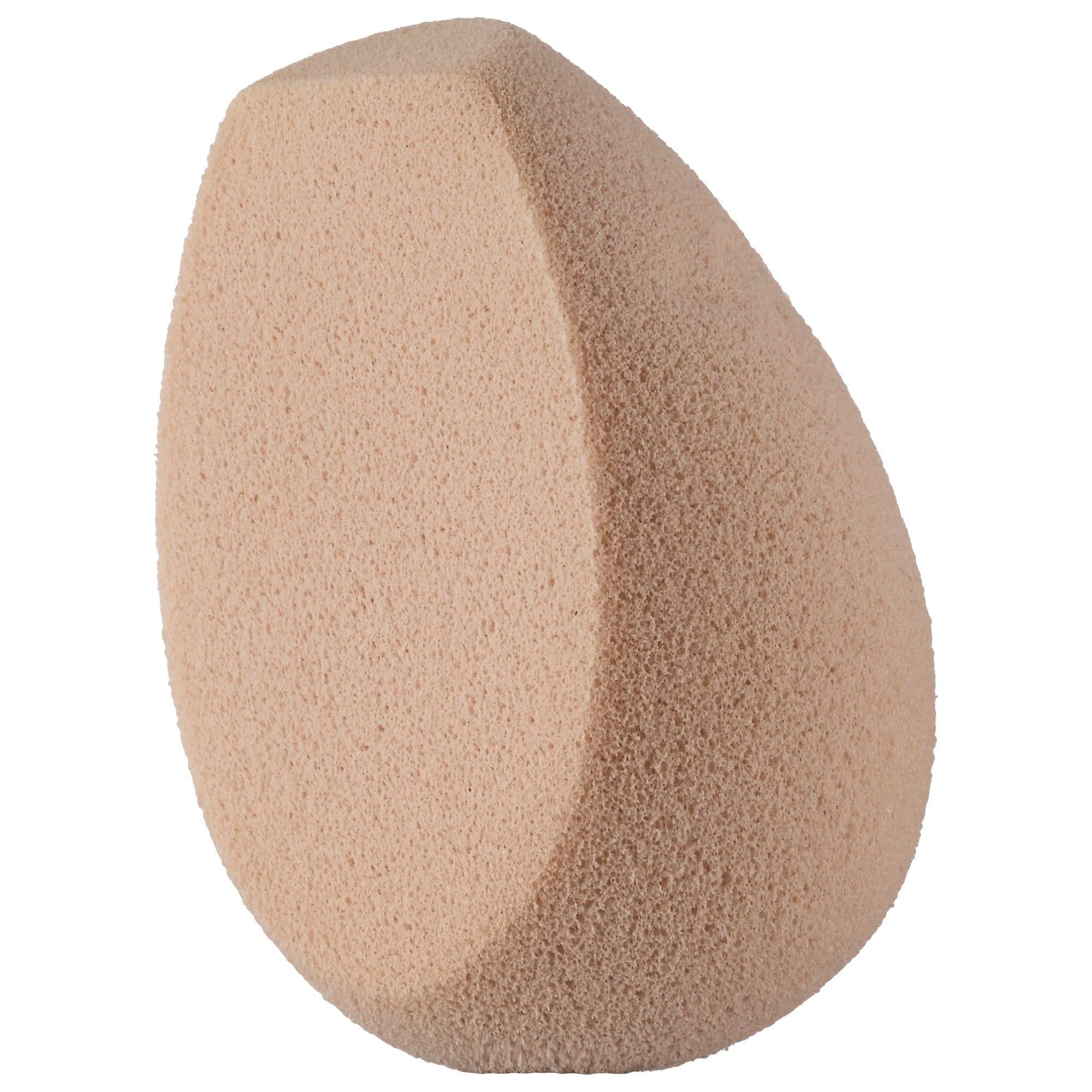 Fenty Beauty Latex-free beige teardrop makeup sponge 100 with angled flat side and rounded edges for smooth, even application of liquid, cream, and powder makeup. Ideal for blending foundation, concealer, contour, and setting products for a flawless finish. Cruelty-free reusable cosmetic applicator on a white background.